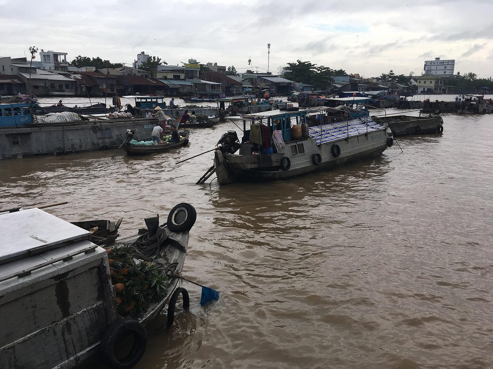 Trading boats moored on the brown river at Cai Rang floating market