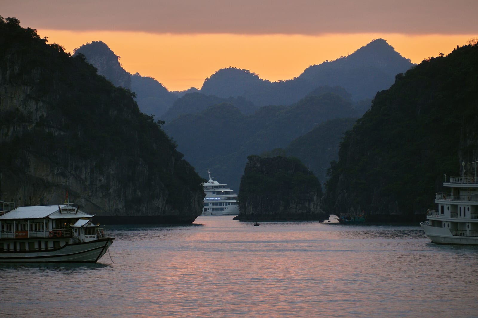 Limestone karsts and tour boats in Ha Long Bay at dusk