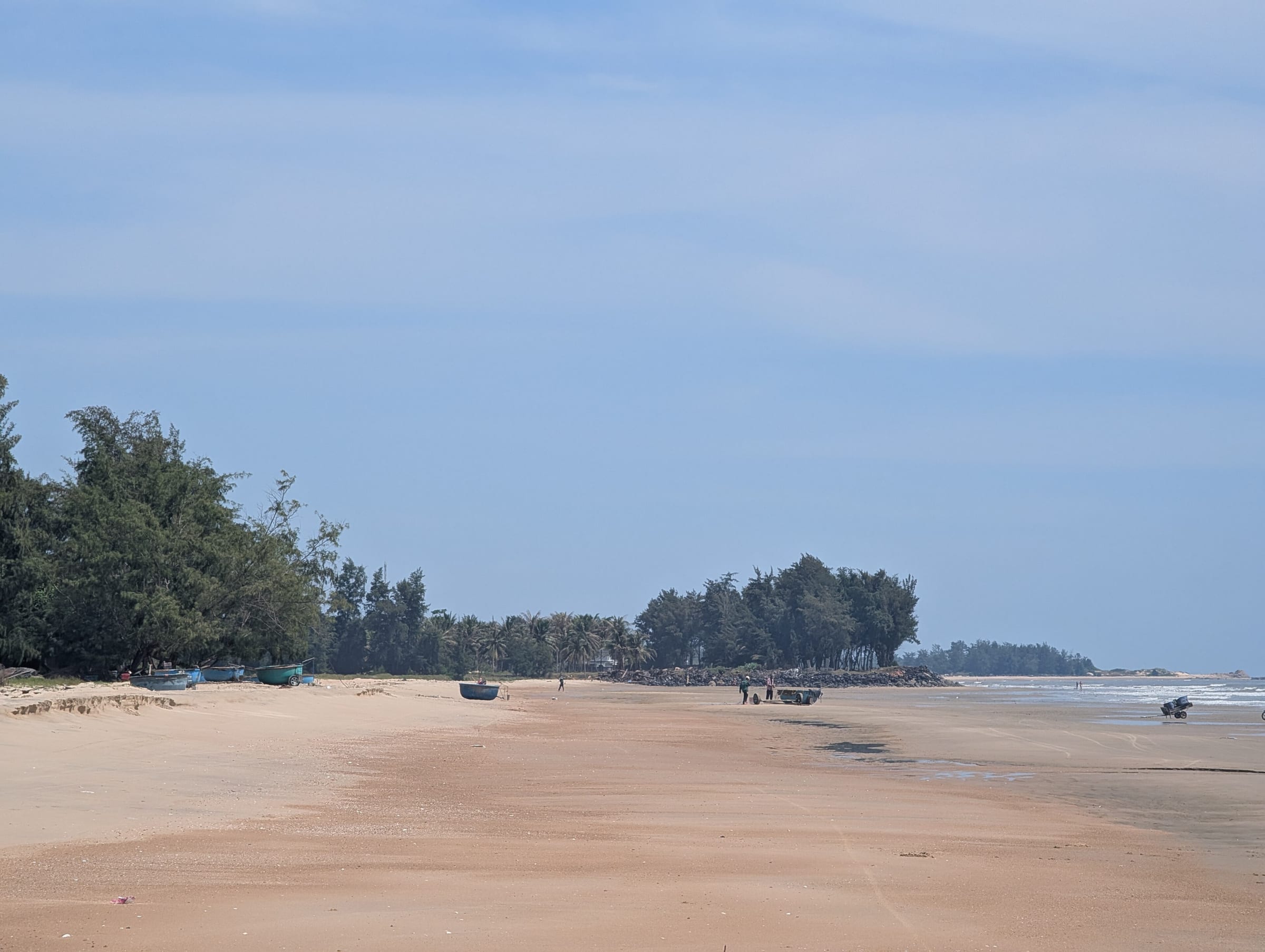 A wide empty sand beach at Ho Tram with casuarina trees along the shore