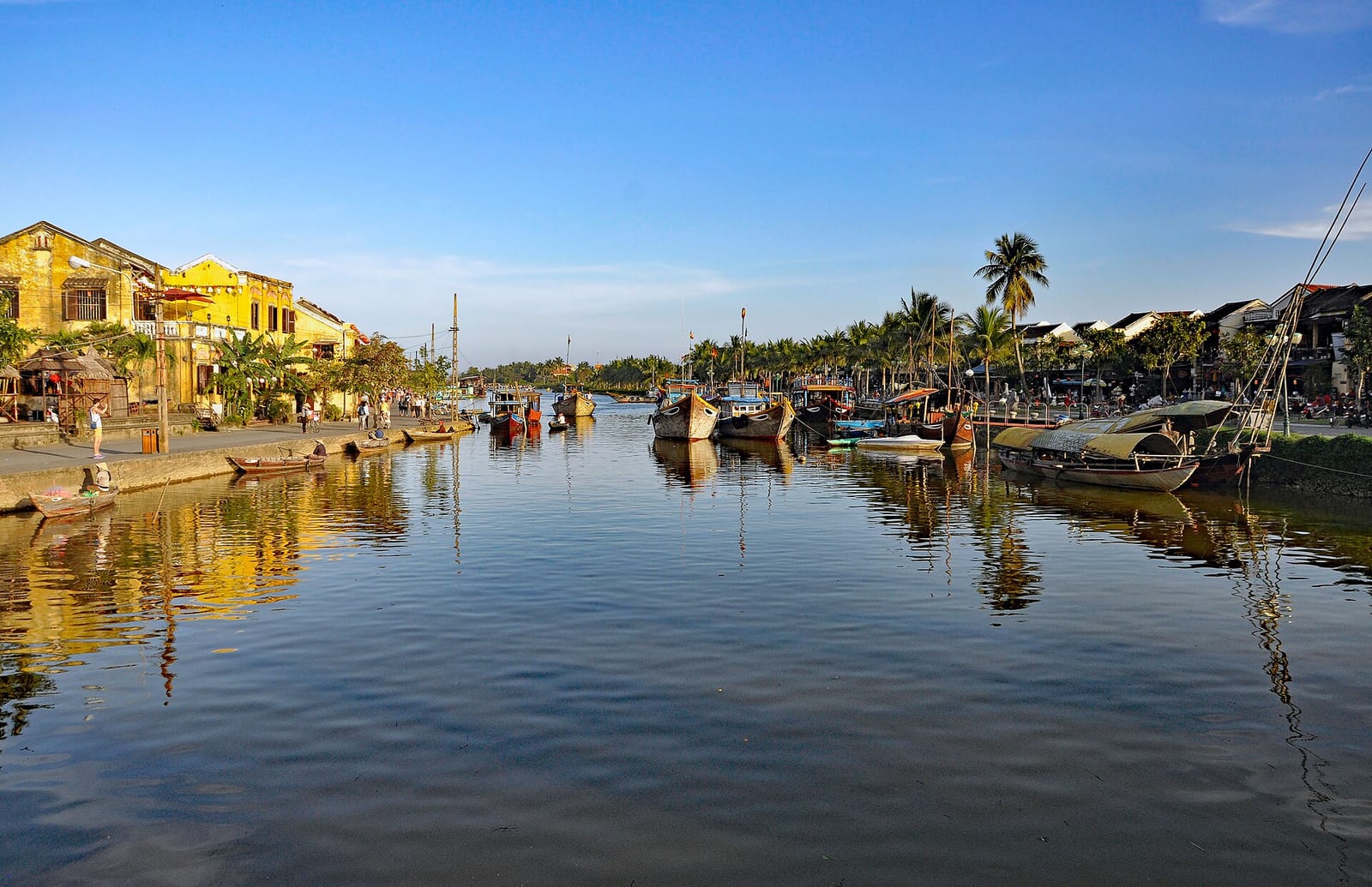 Yellow old town houses and boats along the Thu Bon river in Hoi An