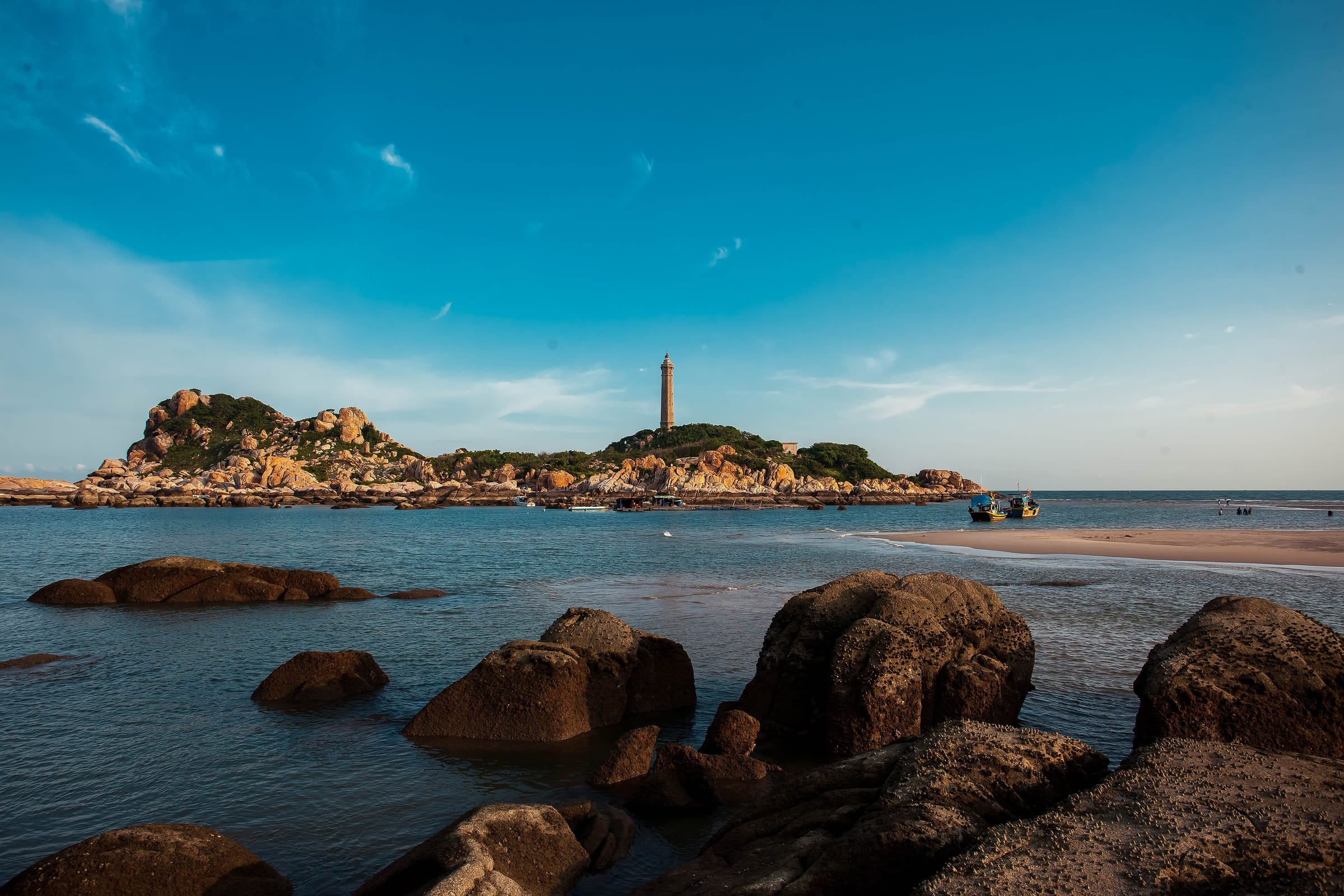 Ke Ga lighthouse on its rocky islet seen across the shallows from the shore