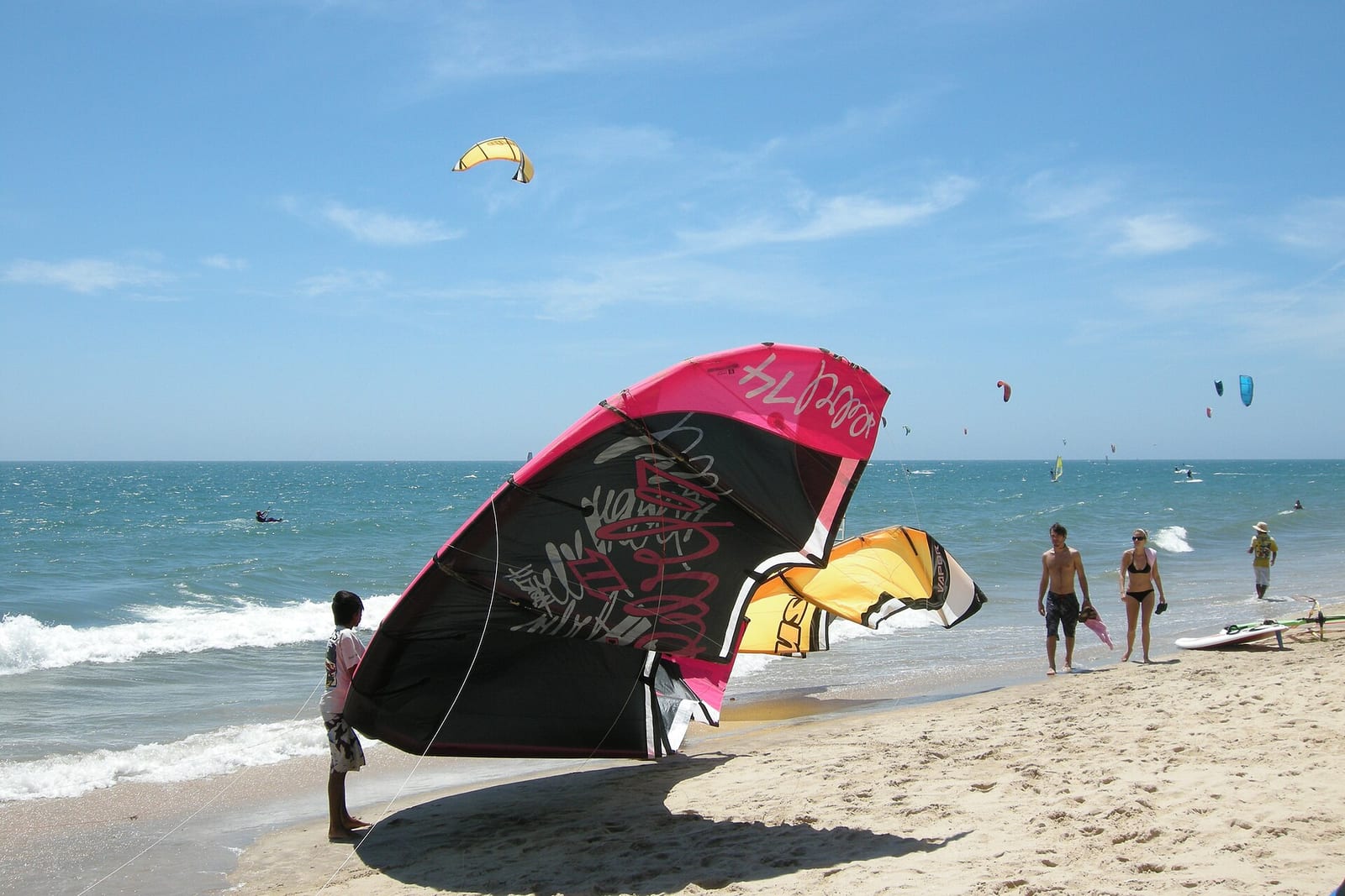 A kitesurf kite laid out on the sand at Mui Ne beach, with the beach strip stretching away