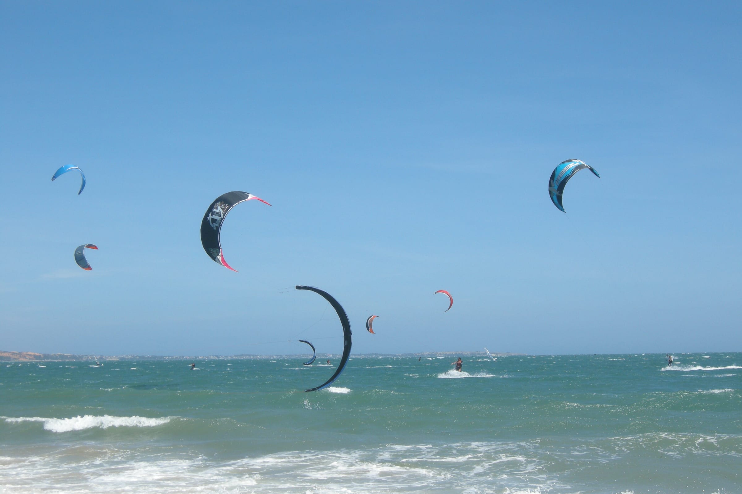 Kitesurfing kites in the air above the waves off Mui Ne beach on a clear day