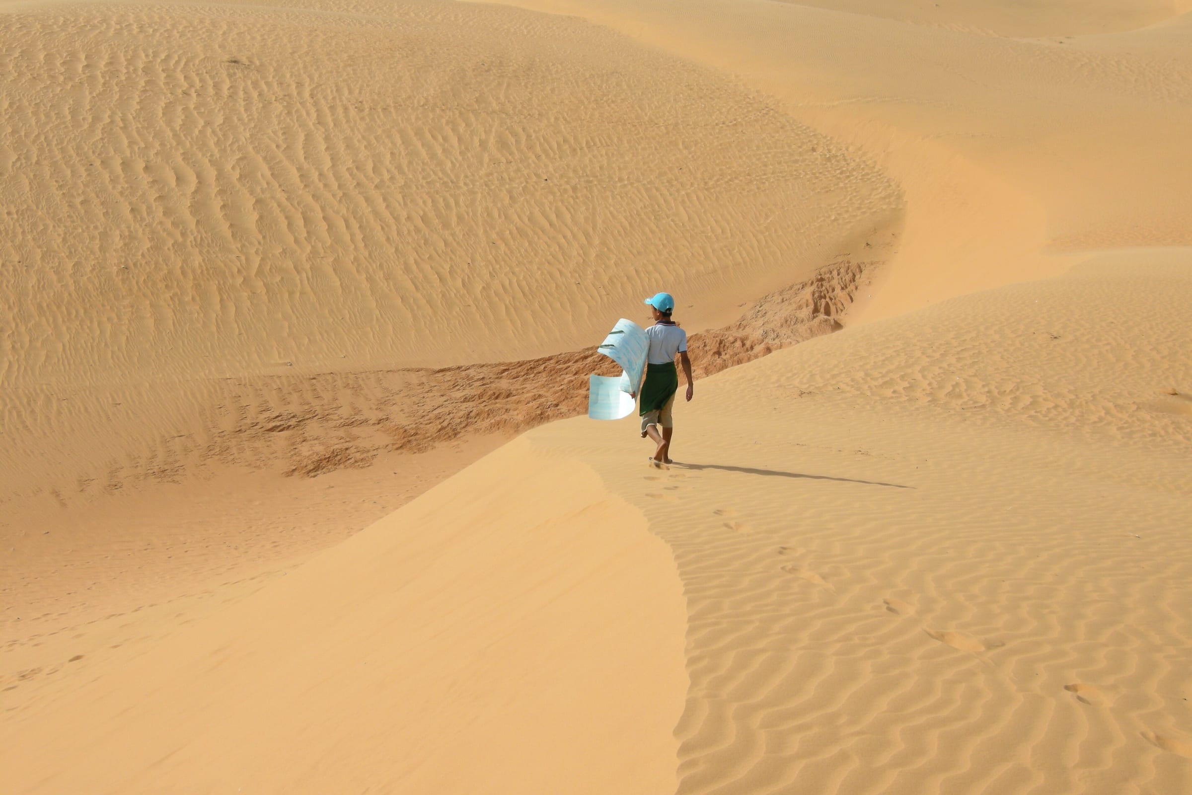 A person walking along a rippled ridge of the Mui Ne sand dunes
