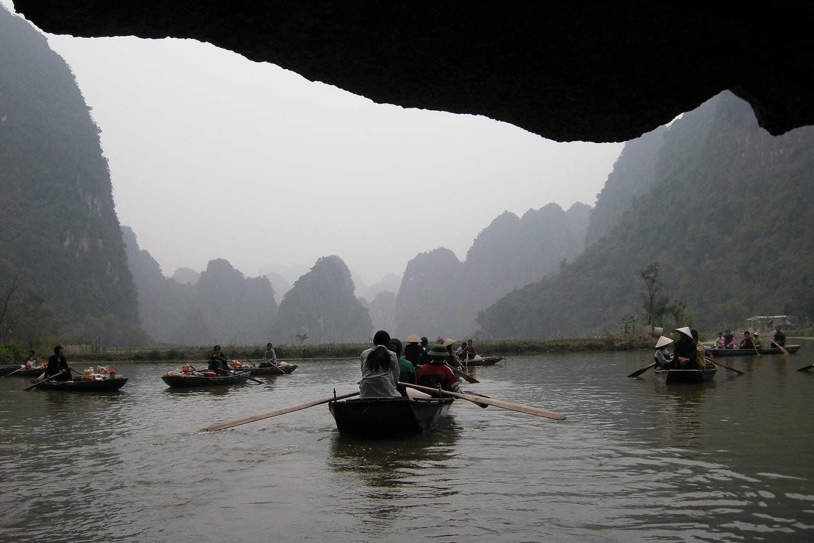 Rowing boats emerging from a cave on the Trang An boat route in Ninh Binh