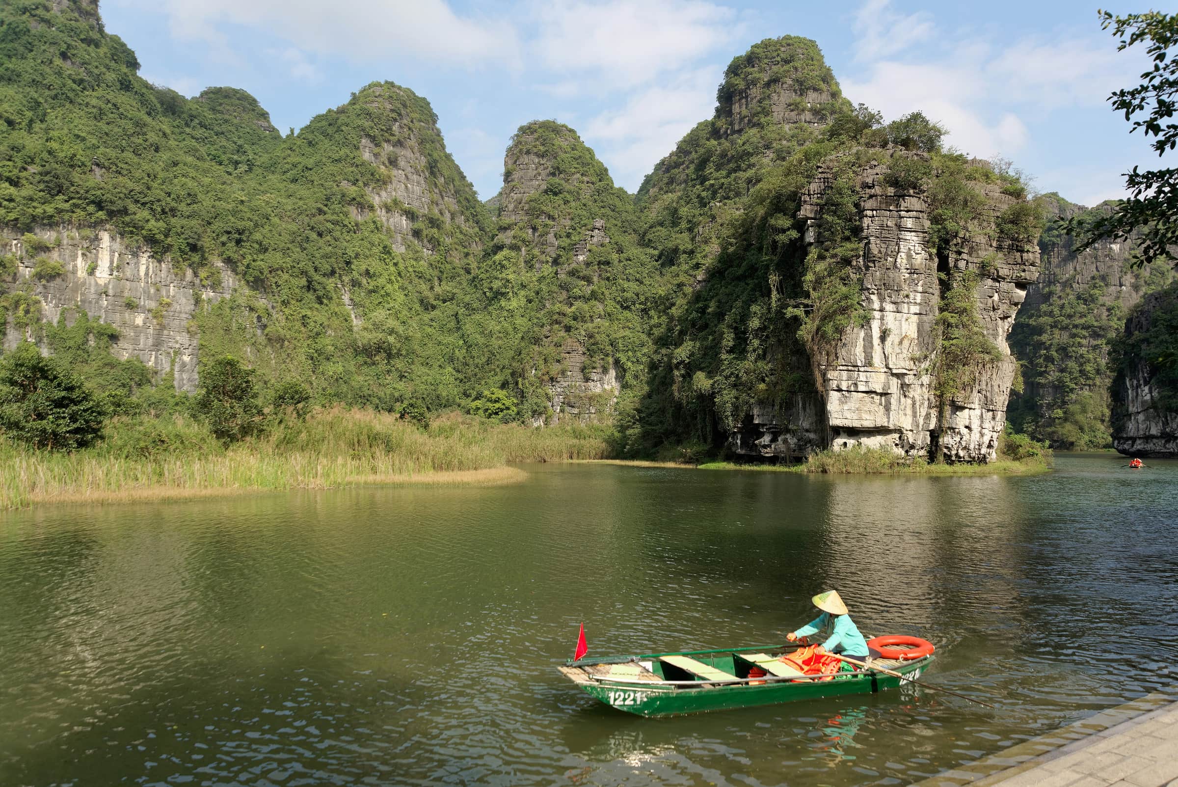 A rowing boat on the green river between limestone karsts at Trang An, Ninh Binh
