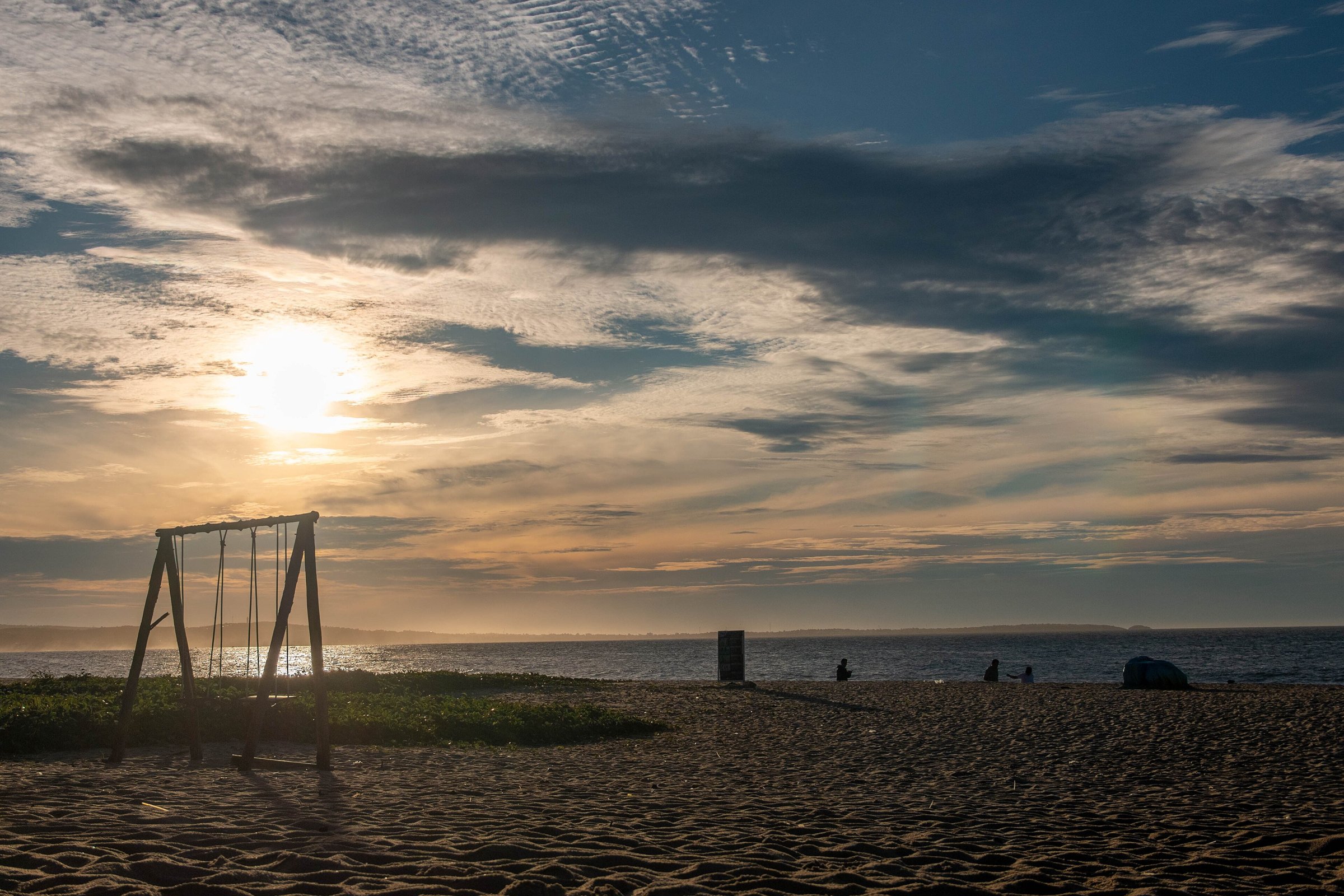 Sunrise over a sandy beach on the Phan Thiet coast, with a swing set in the foreground