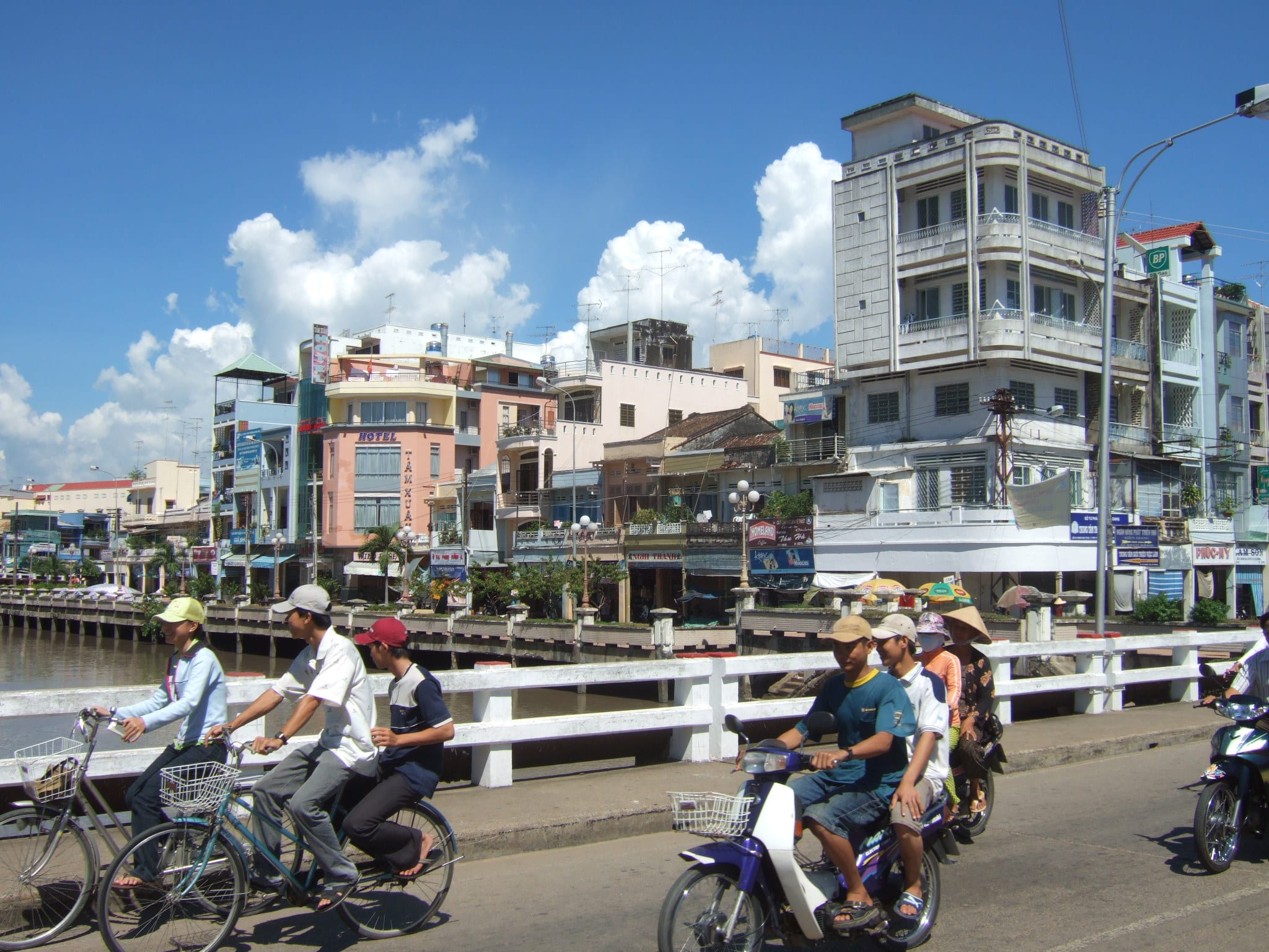 The canal-side street and bridge in the centre of Rach Gia with motorbikes crossing