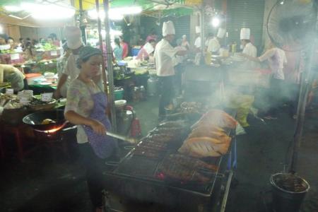 Cooks and a display of dishes at a Saigon night market eatery